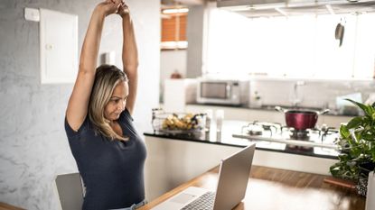 A woman stretching at her desk