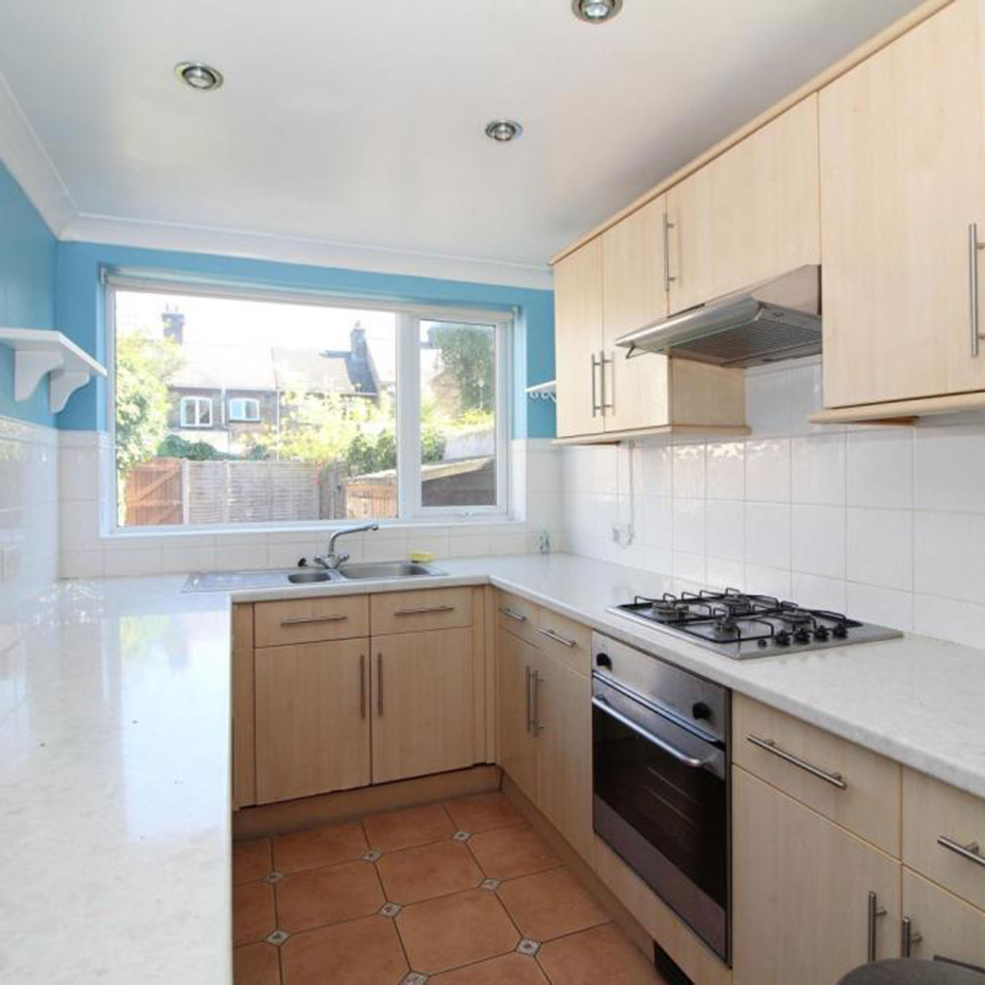 Small kitchen with blue back wall and wooden cabinets
