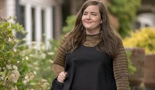 Shrill Aidy Bryant walking down the street with a smile in a black dress