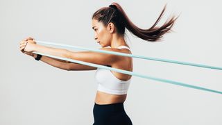 Resistance band workout: Woman pulling a blue resistance band in front of her side on 