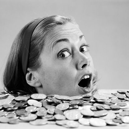 UNITED STATES - CIRCA 1960s: Woman pulling funny face, up to her neck in coins.