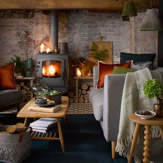 A country cabin with exposed brick walls, a log burner and a grey sofa