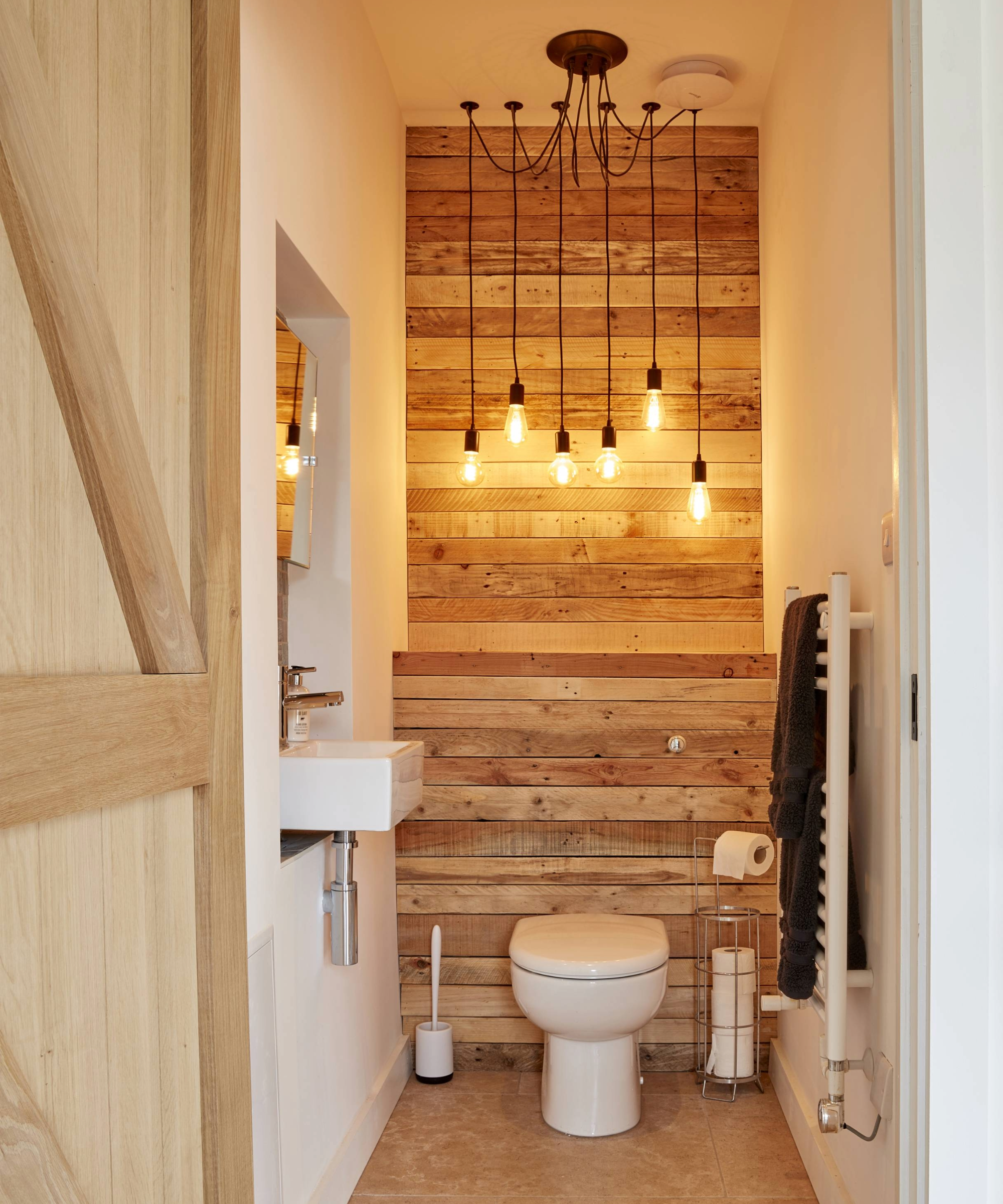 Narrow downstairs toilet with a wooden feature wall behind the toilet and sink to the left hand side