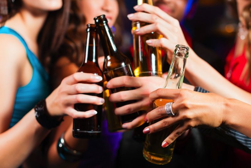 A group of people toasts with beer bottles.