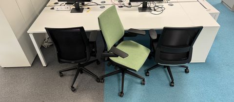 The green Gesture chair in between two generic black office chairs. 