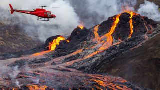 A helicopter flies over the eruption
