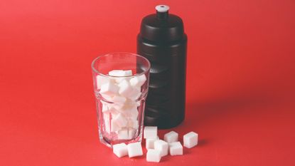 Image shows a glass of sugar cubes next to a cycling water bottle