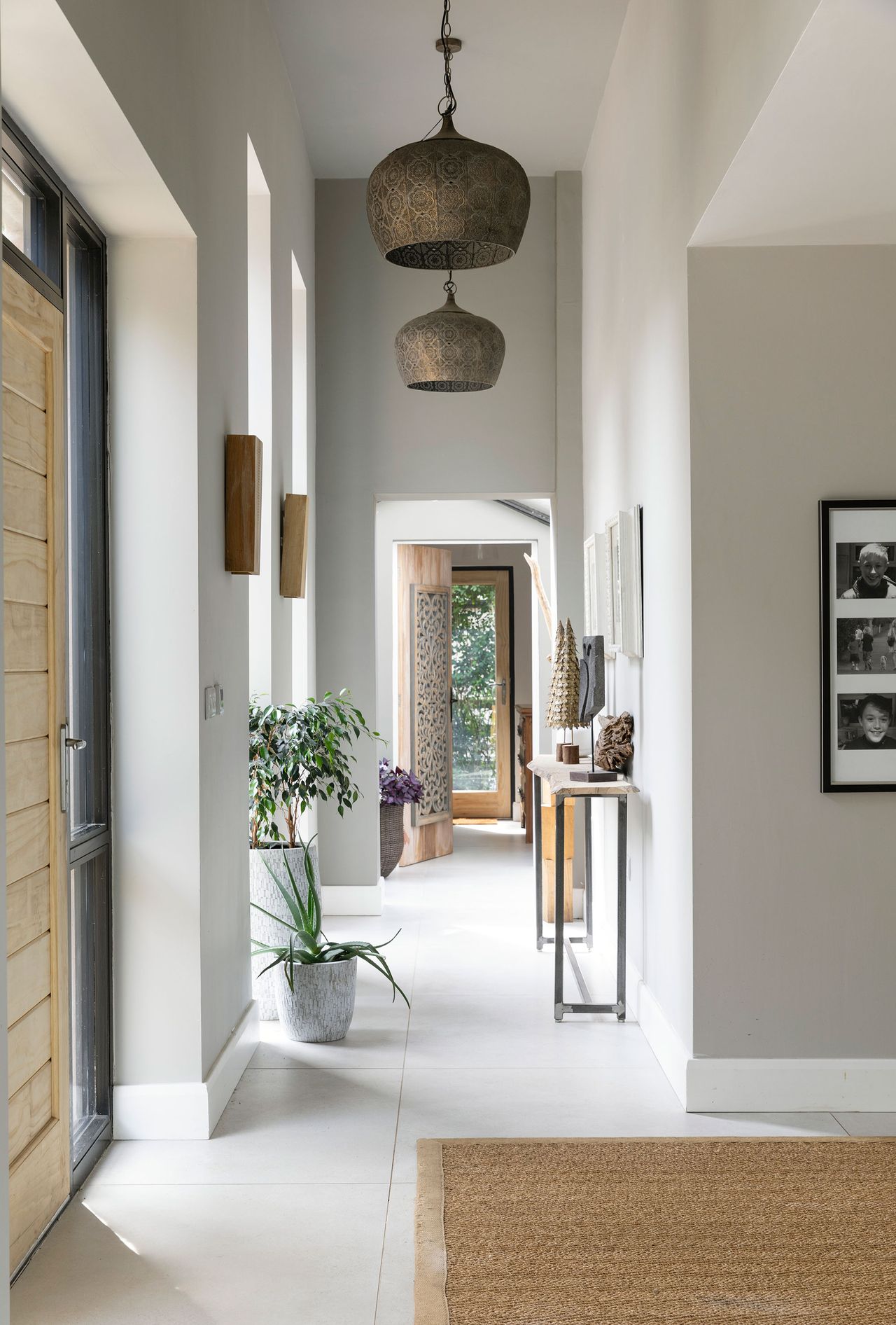 entry way with wooden front door gray green neutral colors and brass pendant lights