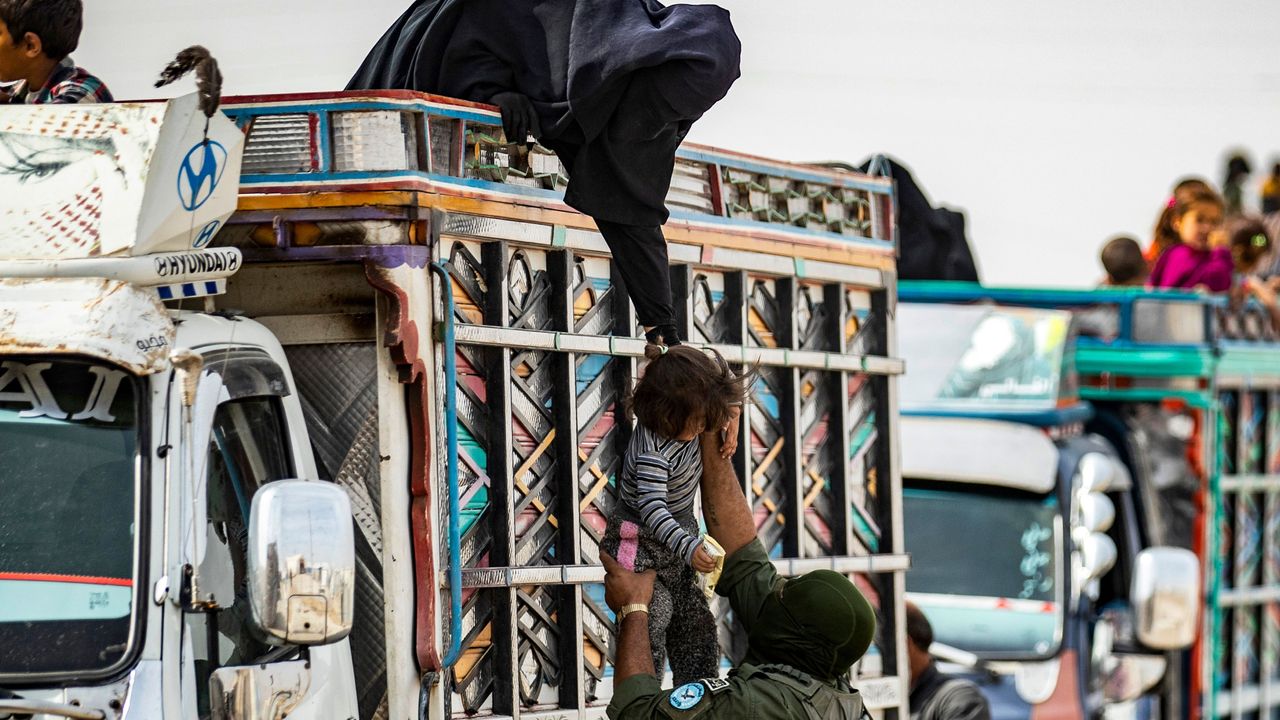 A Kurdish fighter helps a Syrian child board a truck transporting Syrians suspected of being related to Isis.