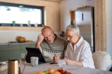 Couple sitting at the kitchen table looking at digital tablet 