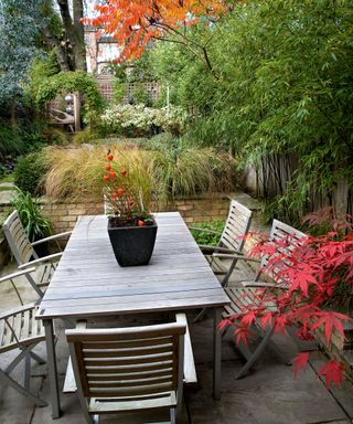 wooden dining table and chairs on a patio in an urban garden in autumn
