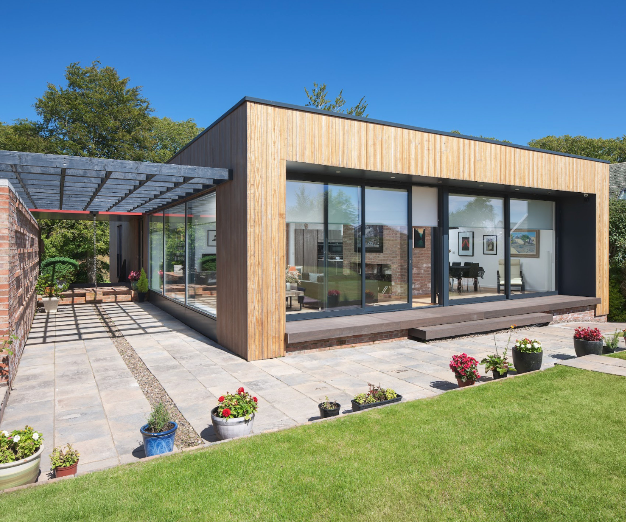 The rear exterior of a modern house with a sheltered courtyard and green lawn