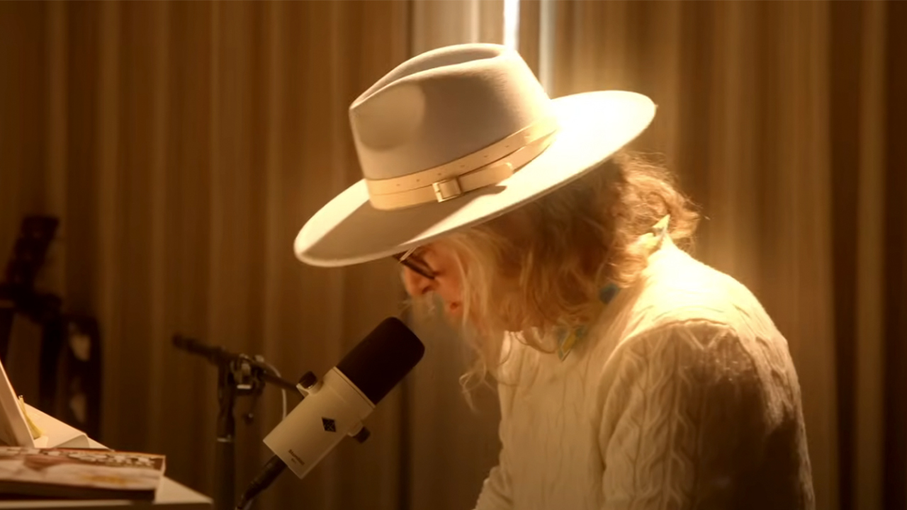 Ed Roland sitting at a piano in all white writing a song