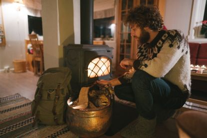 Man sitting near wood stove in cabin