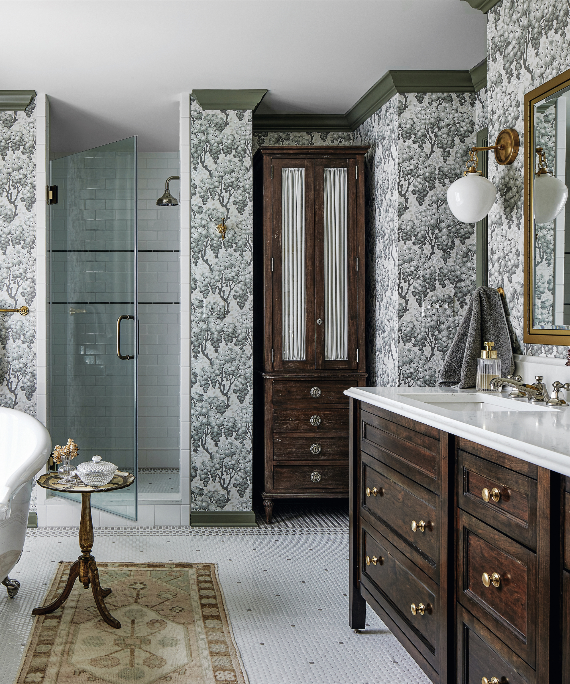 Bathroom with patterned wallpaper and dark wood cabinet and sink uinit and freestanding white bath