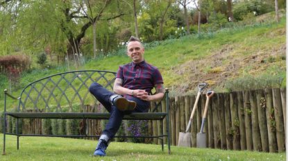 Garden Rescue's Lee Burkhill poses in a verdant green outdoor setting