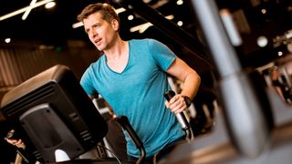 Man using cross-trainer in gym