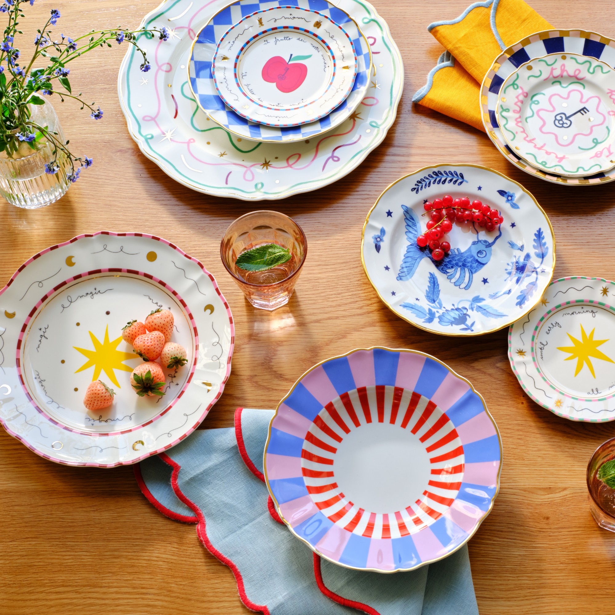 Mismatched Bitossi plates on a wooden dining table