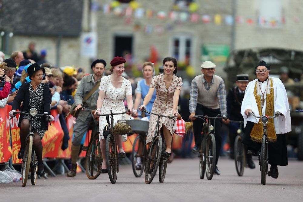 People dressed in world war II era clothing ride toward the team presentation stage.