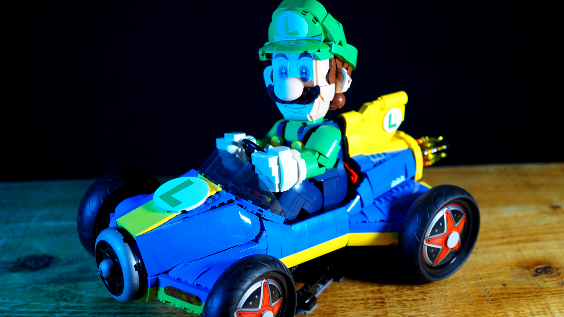Lego Luigi &amp; Mach 8 Kart on a wooden table, in front of a black background