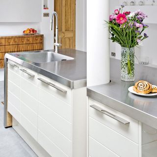 kitchen with steel worktop and flower vase with white drawers