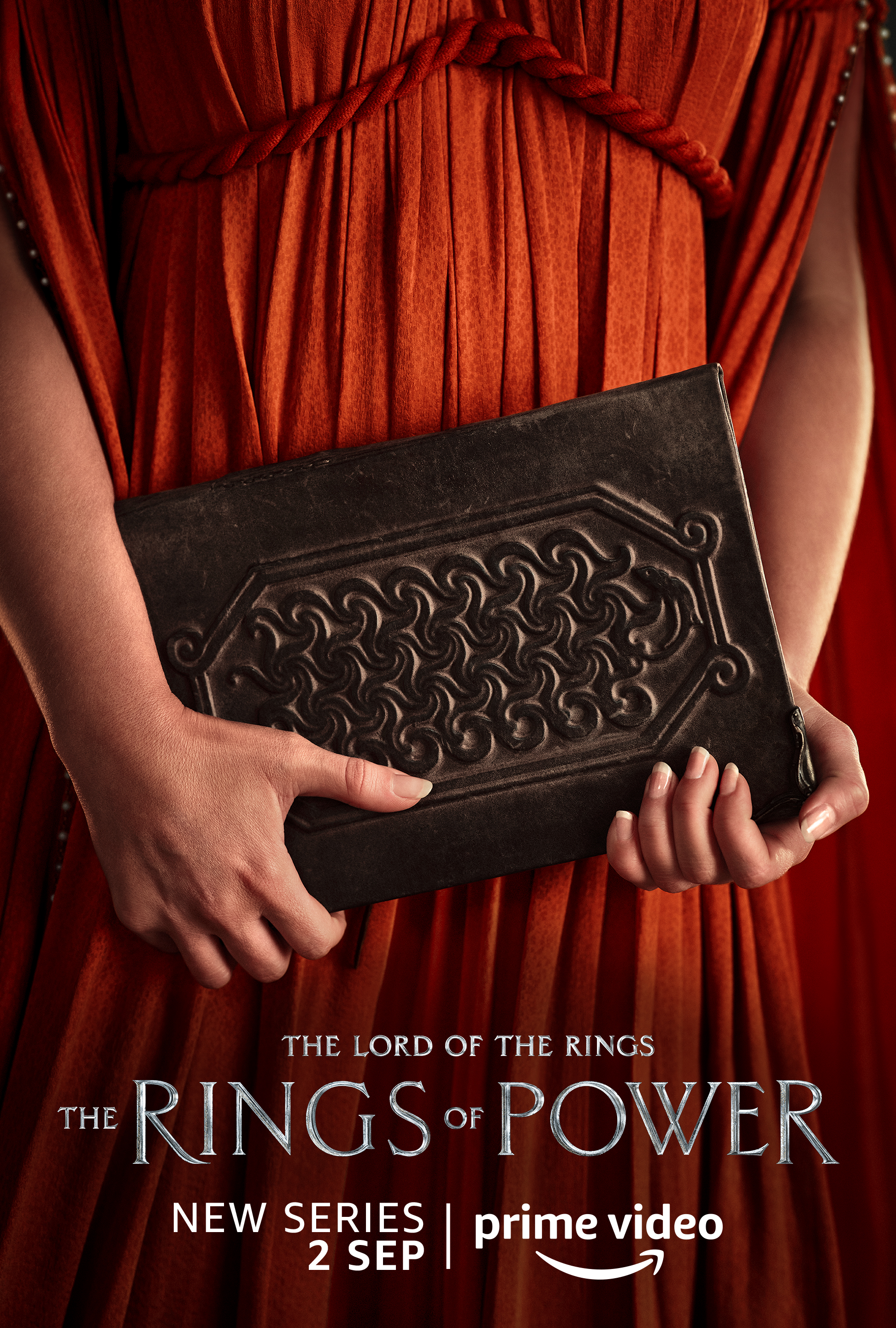 A woman holding a book character poster for Lord of the Rings: The Rings of Power