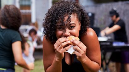 Woman chewing a burger at a barbecue