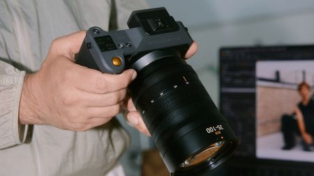 A Hasselblad camera in photographer's hands, alongside a Macbook with the Capture One software on the display
