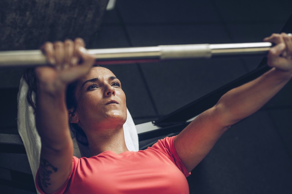 Woman performs close-grip bench press in gym