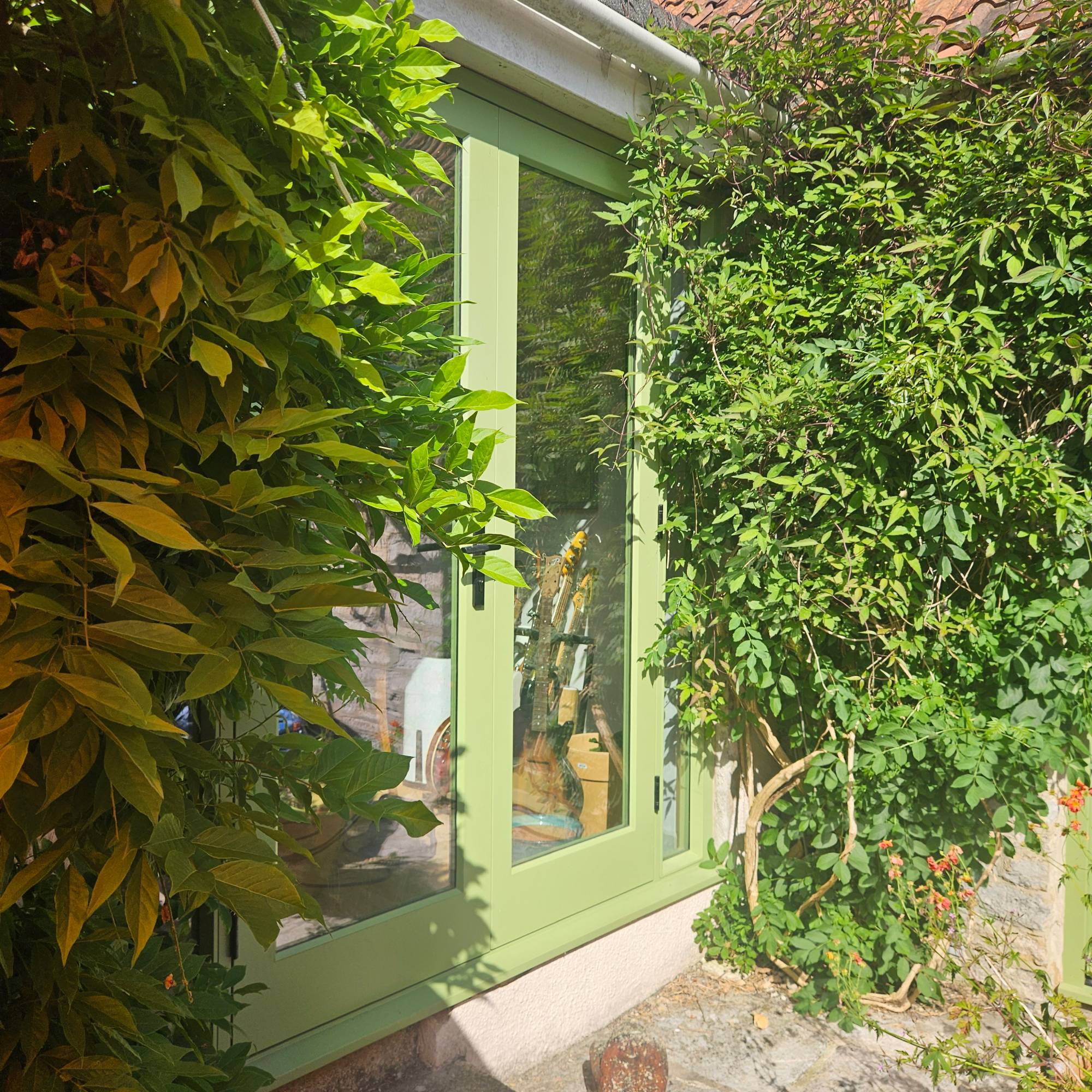 green patio doors with large foliage trees either side