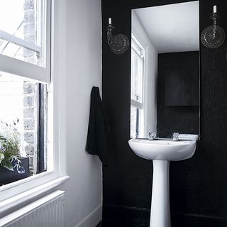 bathroom with black wall and mirror and washbasin