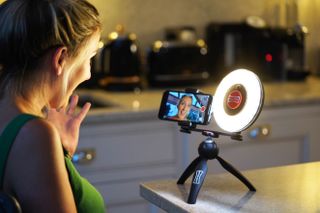 A young person filming themself using the Rotolight Ultimate Vlogging Kit on a table