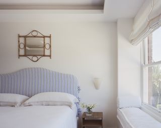 A cream toned bedroom with a blue headboard, and white bedding