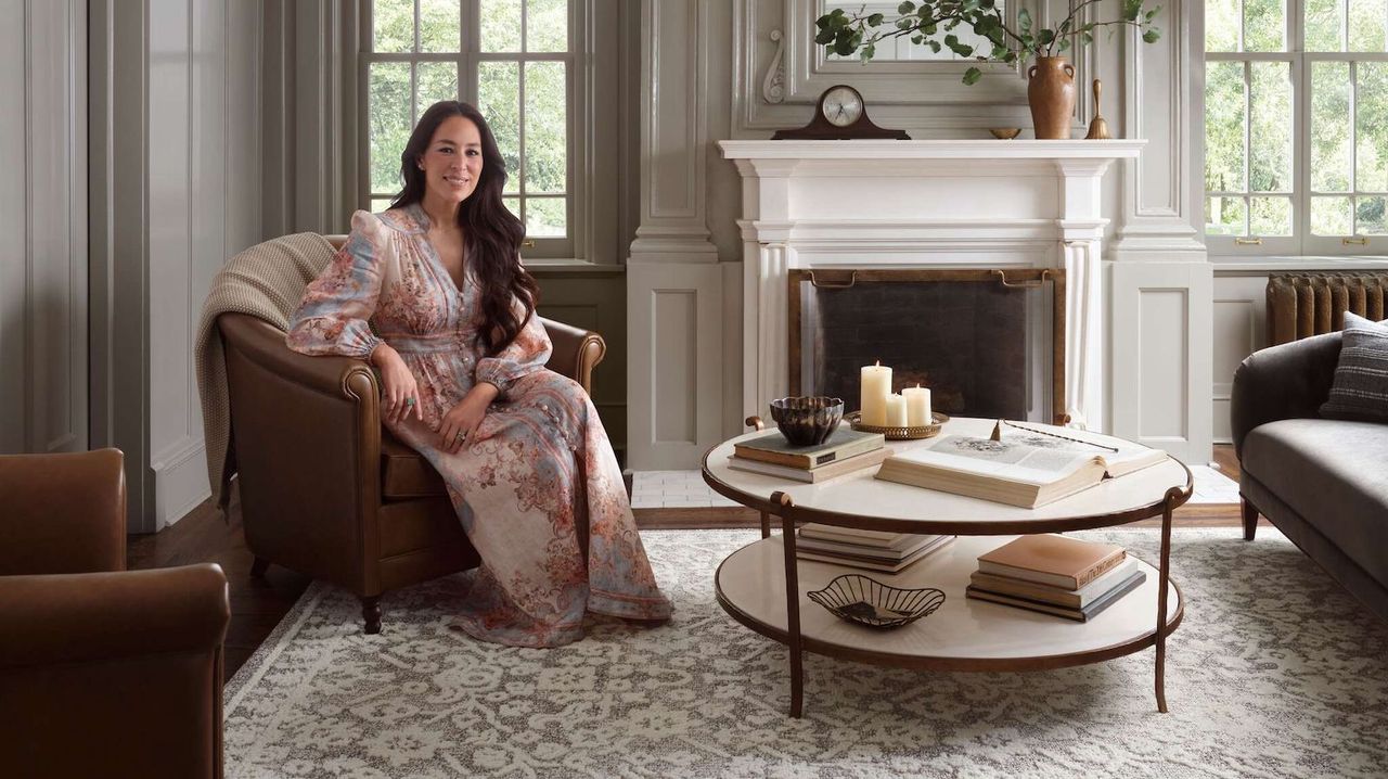 Joanna Gaines in a living room amongst Magnolia Home by Joanna Gaines x Loloi collection it&#039;s neutral styled