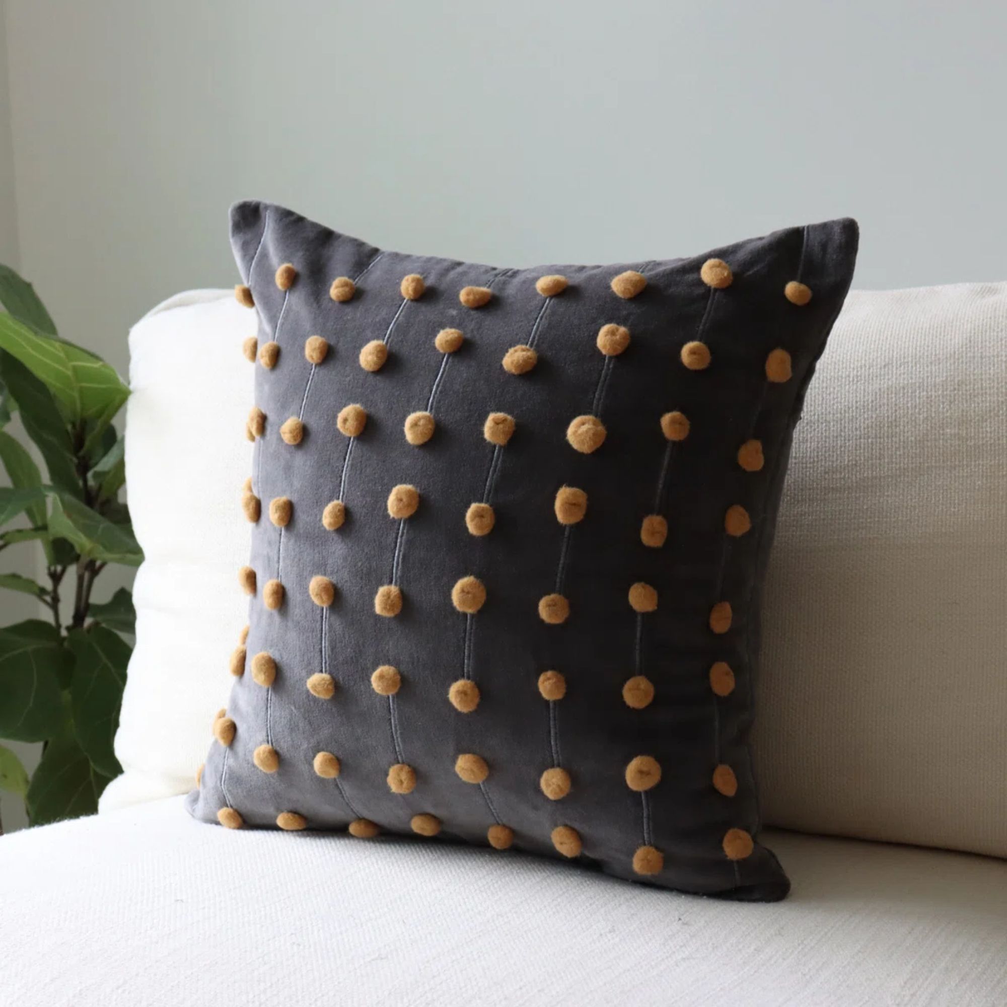 Gray pillow with yellow pom poms