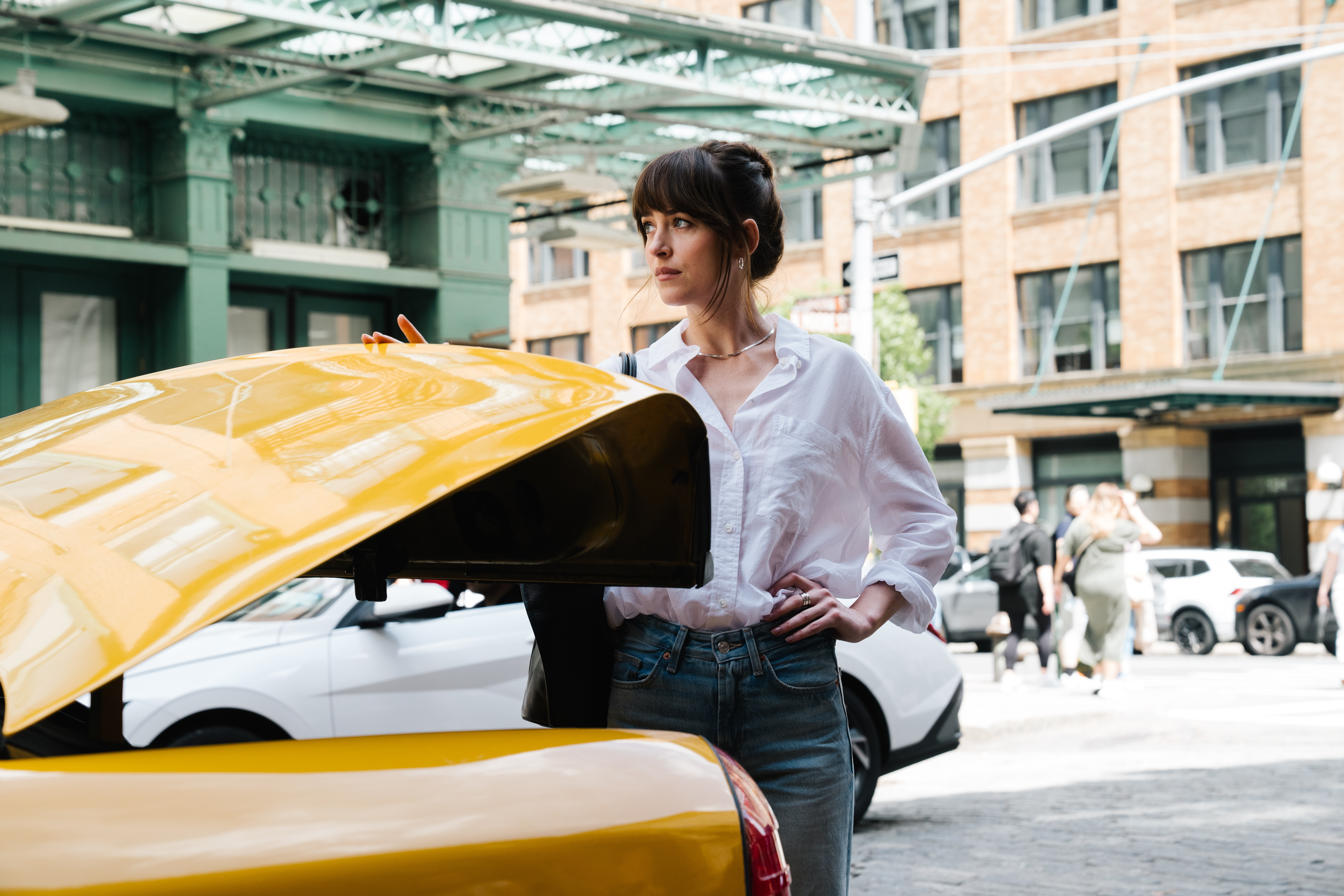 dakota johnson closing the trunk on a taxi in new york city in a still from the movie materialists
