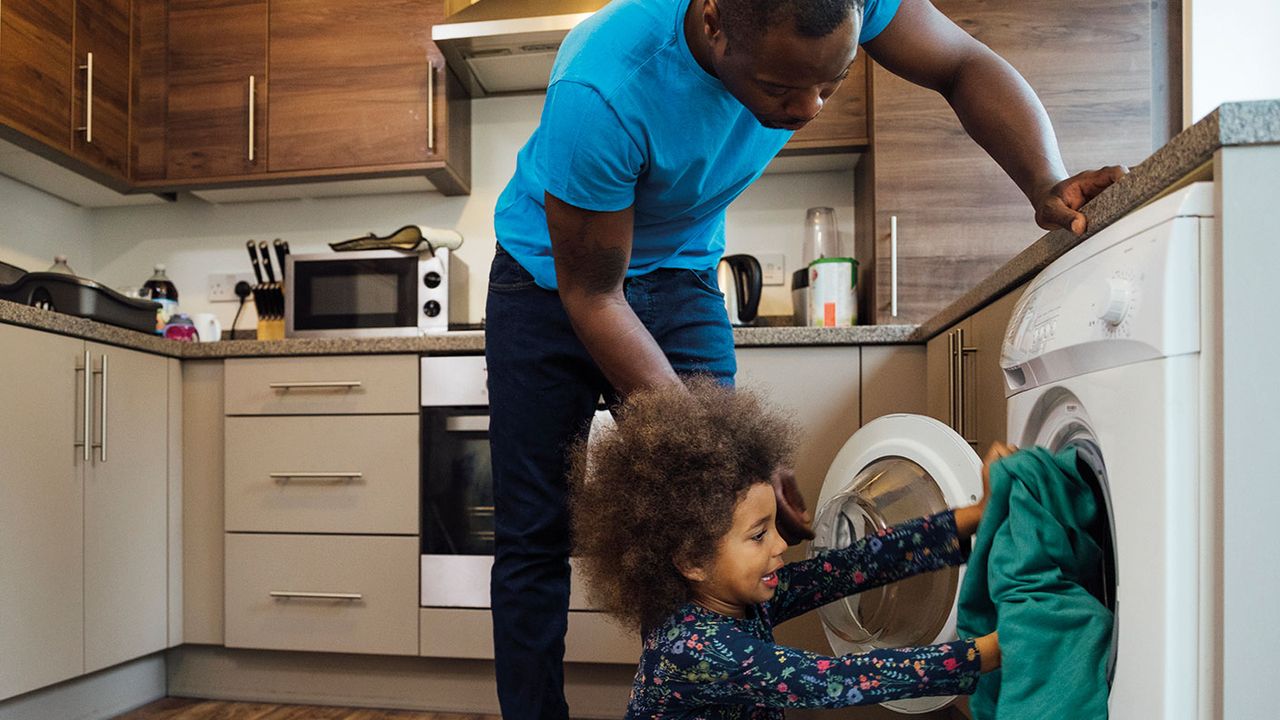 Father and child putting clothes in a washing machine