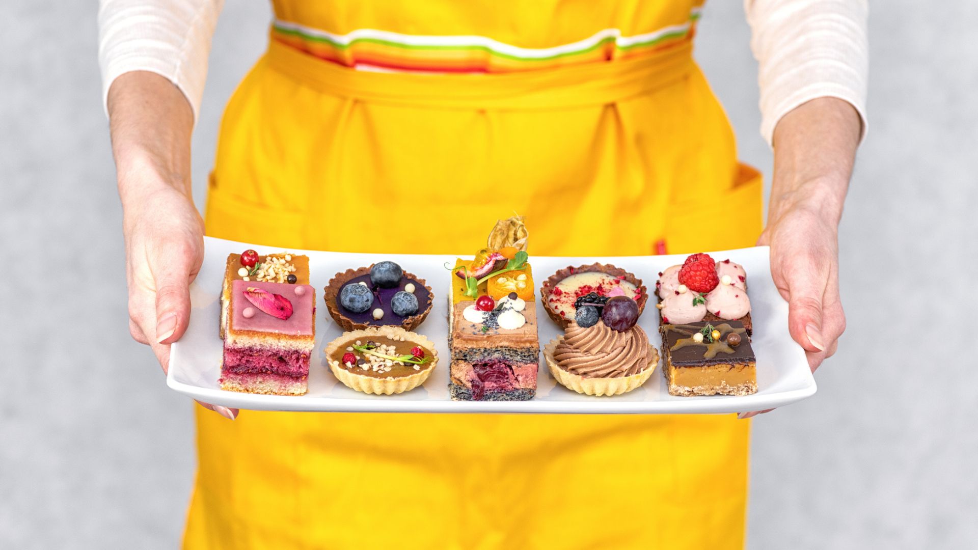 A woman holds a platter of patisseries