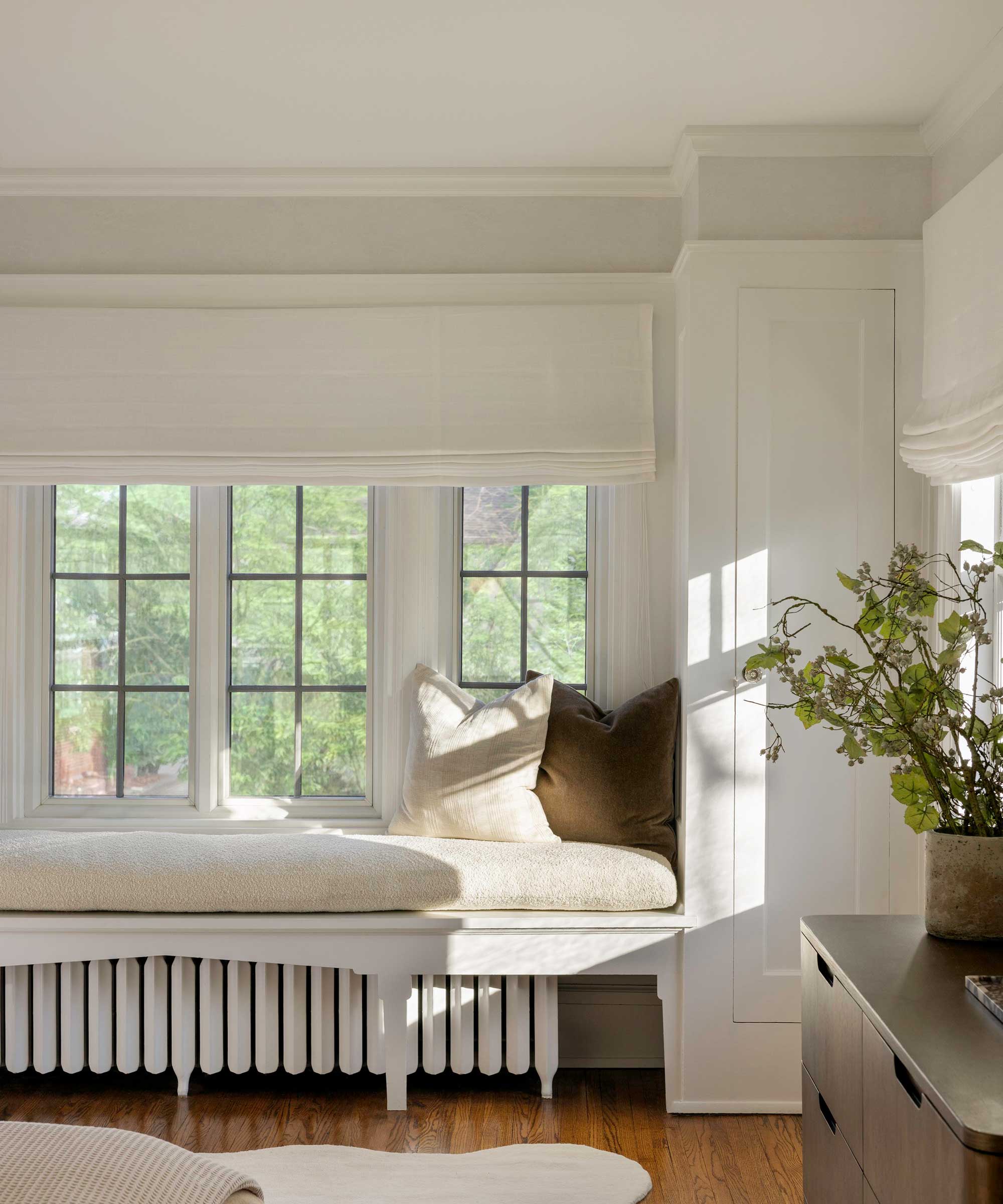 cozy window seat with beige cushions and cream Roman blind