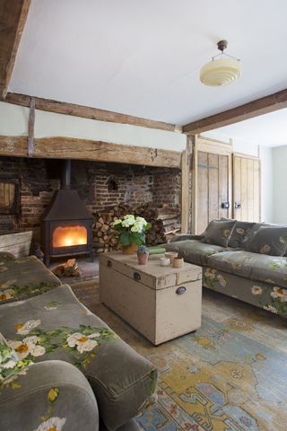 living_room_floral_sofa_rug_fireplace_fire_beams_brick_exposed
