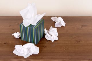 A box of tissues with used tissues around it.