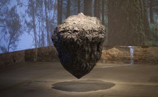 A textured, acorn-shaped sculpture which appears to hover
