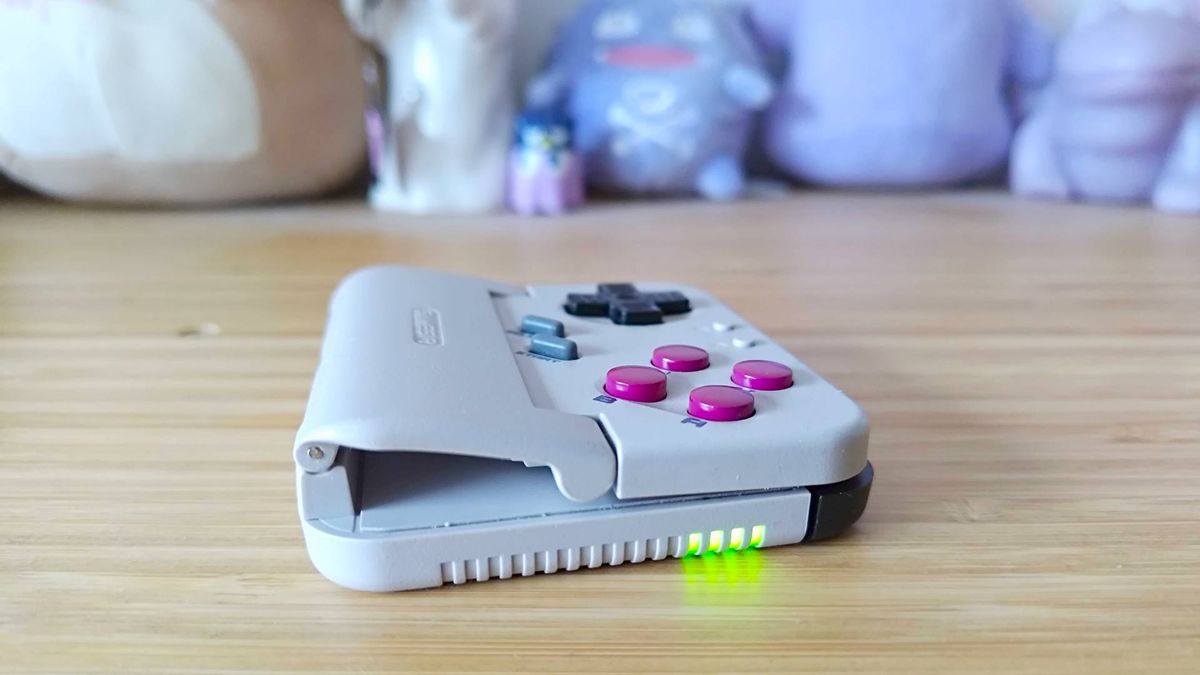 Side view of GameSir Pocket Taco with hinge and green LED indicator lights in view on woodgrain unit.