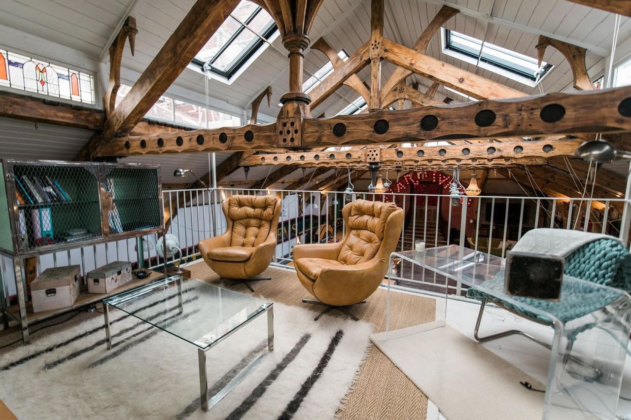 The upstairs to the open-plan living room with two leather chairs and the V-shape timber frame roof