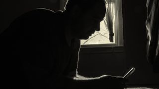A man looks at his phone in a dark room.