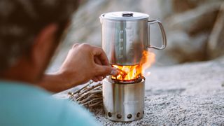 A camper adjusts the flame on their camping stove