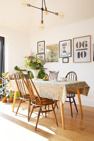 Dining area with tapered leg table, Ercol chairs, gallery wall and Sputnik-style pendant light