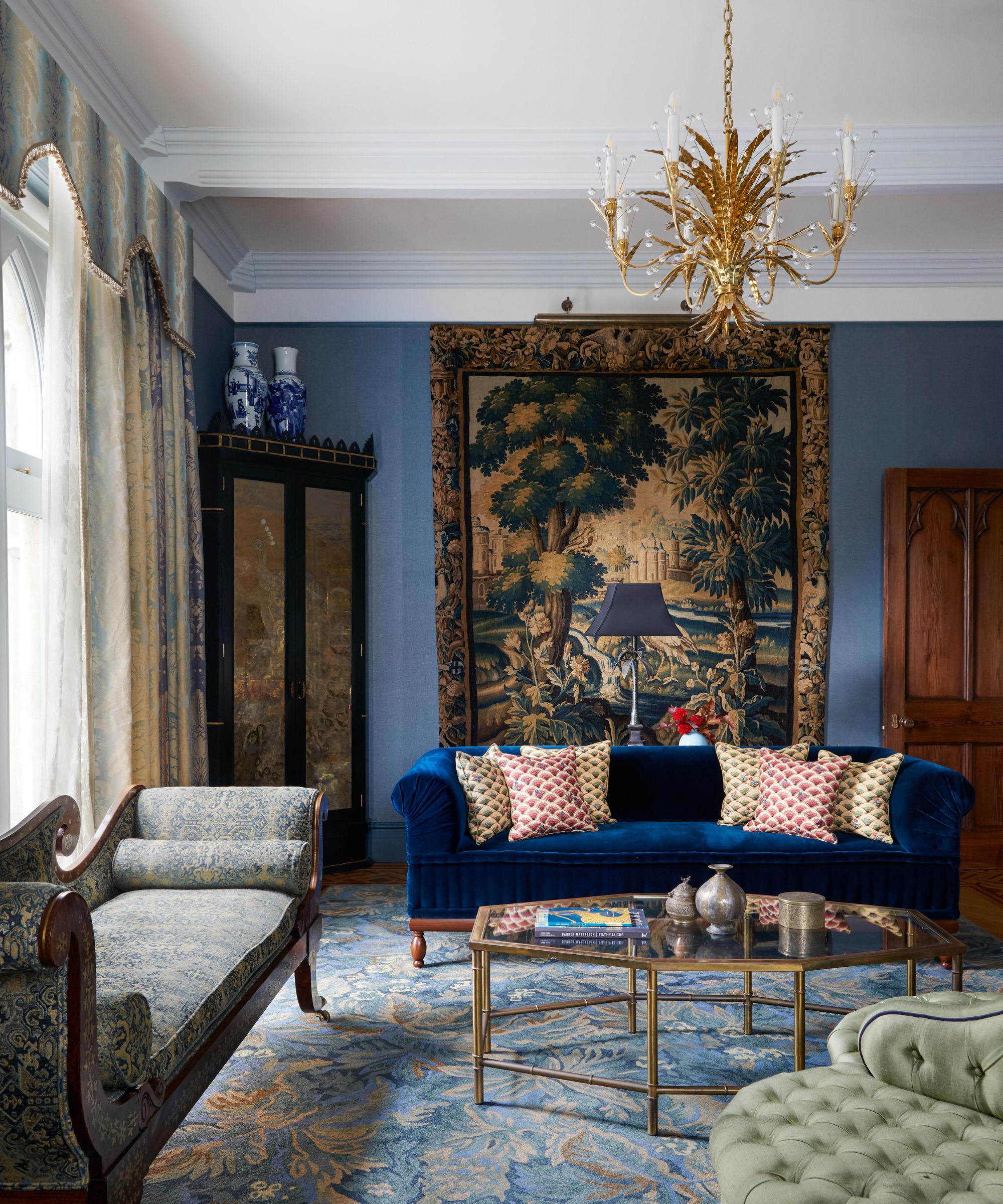 A Gothic living room decorated with a wall tapestry and dark blue hues