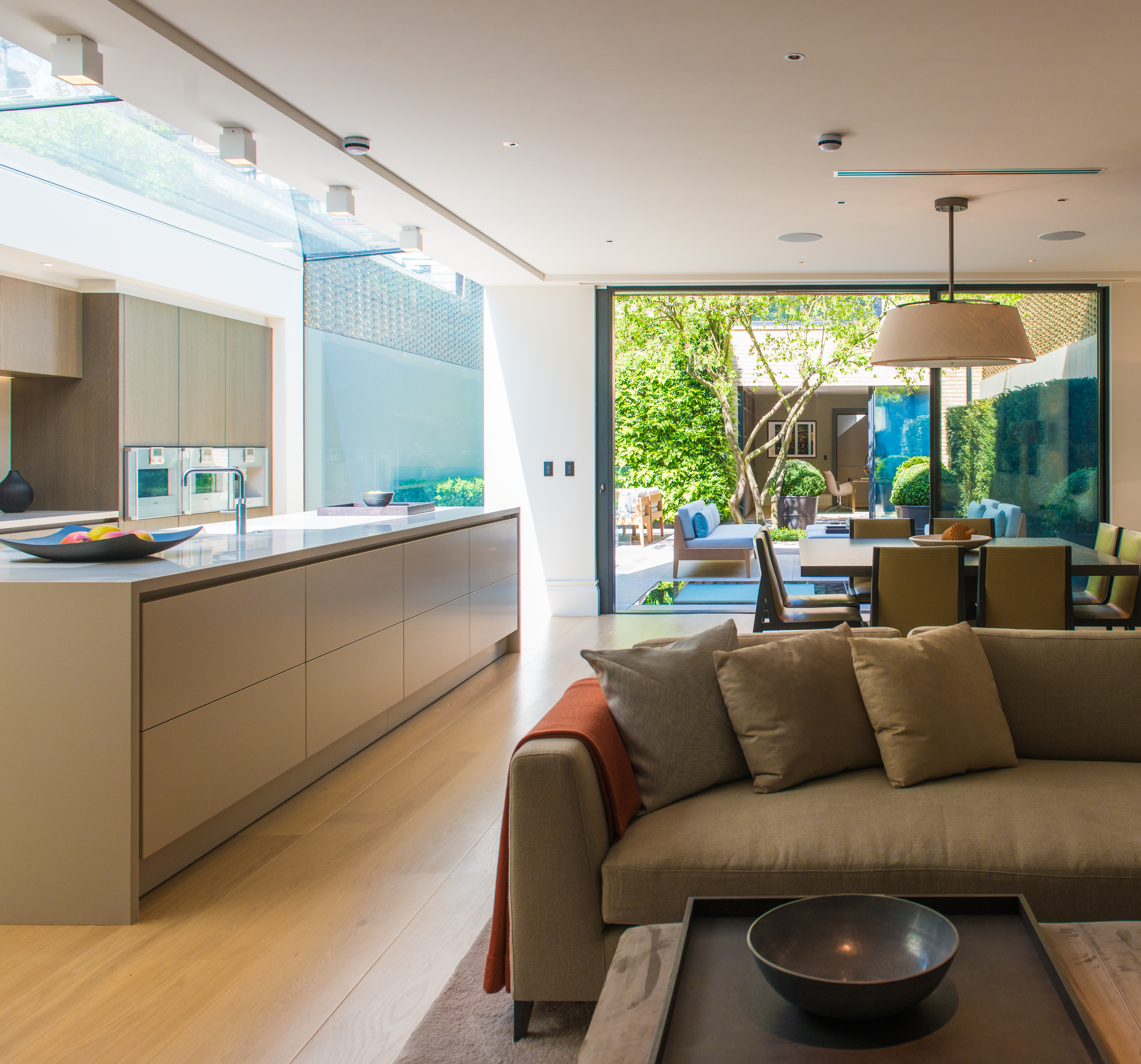 A long, open kitchen and a sofa placed in front of it with a large coffee table in the middle
