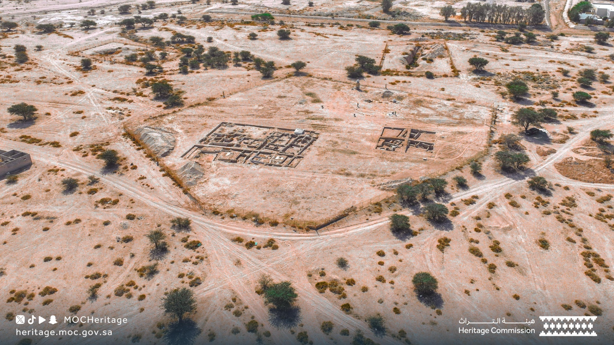 aerial view of an archaeological site in the desert with four open squares of excavation